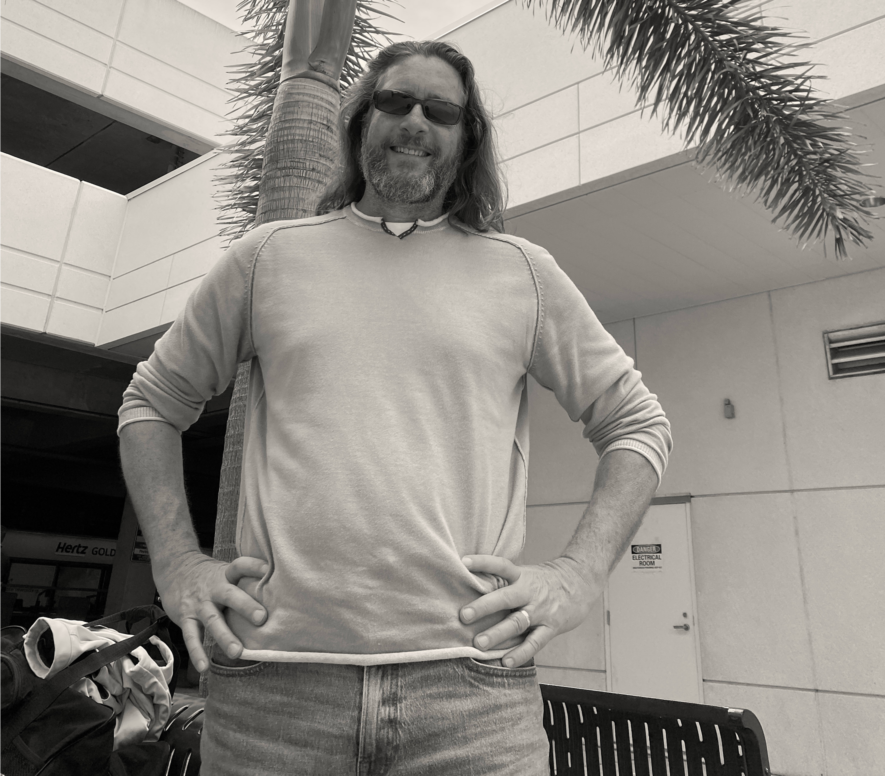 Tall man posing under a palm tree