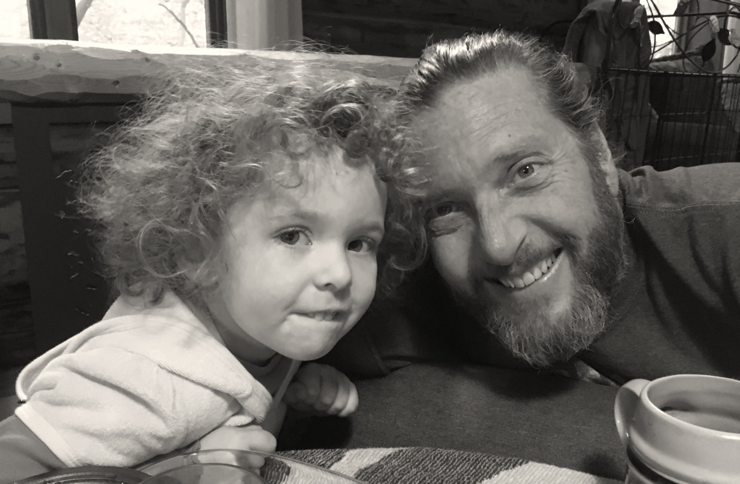 Man and child smiling closely together indoors.