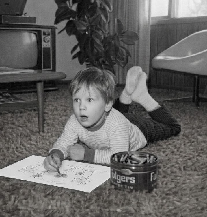 Child drawing with crayons on carpet.